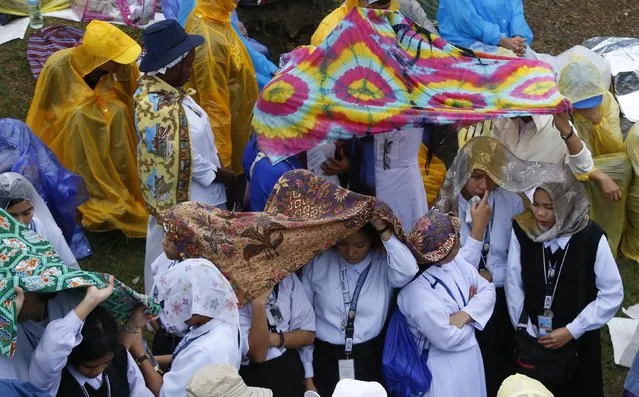 Nuns shield themselves from the rain as thousands of people gather at Rizal Park to attend a mass by Pope Francis in Manila January 18, 2015. (Photo by Erik De Castro/Reuters)