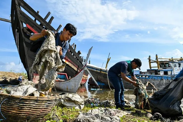 University students clean up plastics and other debris washed ashore at a port in Banda Aceh on May 21, 2023. (Photo by Chaideer Mahyuddin/AFP Photo)