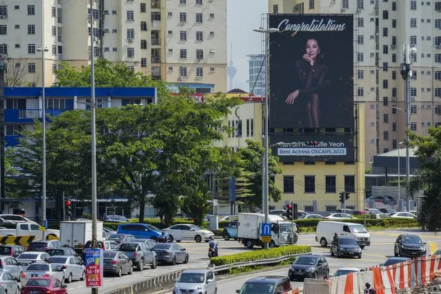 Motorists pass by a giant electronic billboard set up to congratulate Michelle Yeoh on winning the Oscar best actress award in Kuala Lumpur, Malaysia Tuesday, March 14, 2023. (Photo by Vincent Thian/AP Photo)