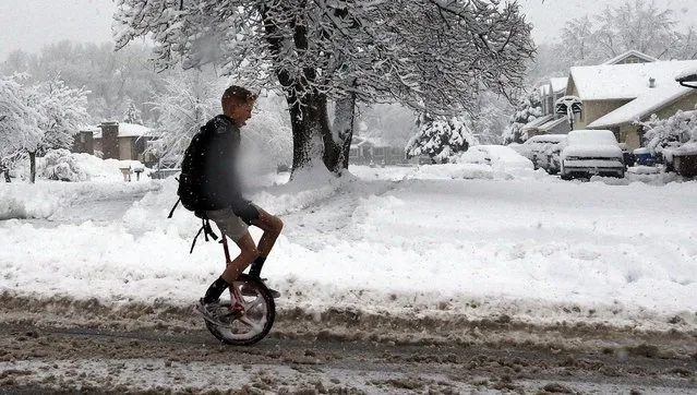 A boy wearing shorts rides a unicycle to school in the snow in Farmington, Utah, Monday, December 14, 2015. Cities along the Wasatch Front received anywhere from six to eight inches of snow overnight. (Photo by Ravell Call/Deseret News via AP Photo)