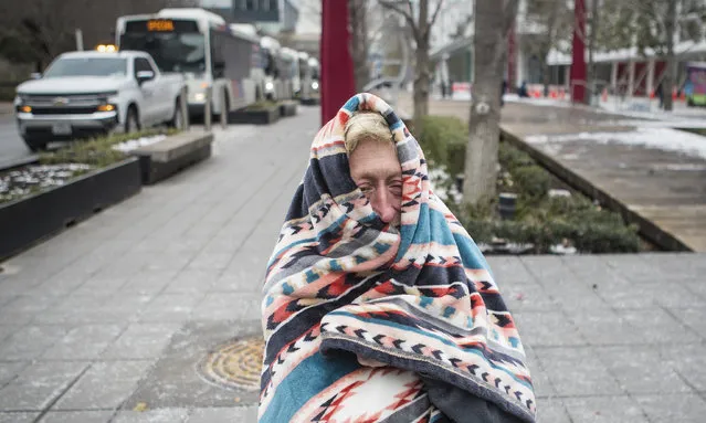 Michelle DeFord bundles up in a blanket to stay warm outside the warming shelter at the George R. Brown Convention Center, where she is staying during the frigid cold weather Tuesday, February 16, 2021, in Houston. Temperatures stayed below freezing Tuesday. A winter storm in the United States that left millions without power in temperatures that plunged as low as minus 39C has claimed at least 20 lives. (Photo by Brett Coomer/Houston Chronicle via AP Photo)