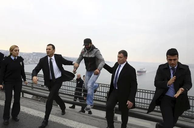 Security officers of Turkish President Tayyip Erdogan take a man, identified by Turkish media as Vezir Catras (C), who was about to jump off the Bosphorus bridge, to the presidential motorcade in Istanbul, Turkey December 25, 2015, in this handout photo provided by the Presidential Palace. According to Erdogan's press office, Erdogan prevented the man from making a suicide attempt, while passing over the bridge in his motorcade. (Photo by Yasin Bulbul/Reuters/Presidential Palace)