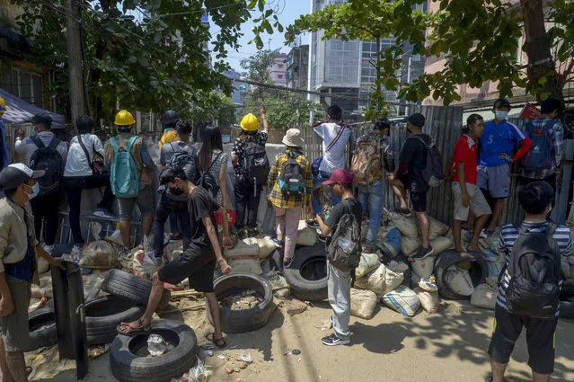 Anti-coup protesters standing behind makeshift barricades watch a line of riot policemen in Yangon, Myanmar Wednesday, March 10, 2021. (Photo by AP Photo/Stringer)
