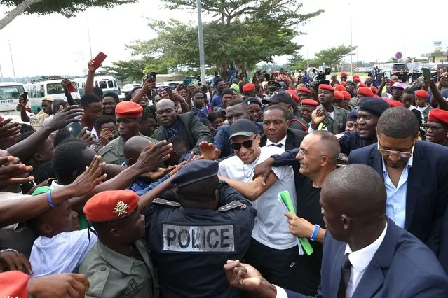 Paris Saint-Germain and France national football team star striker Kylian Mbappe (C) greets crowds gathered outside at the Yaounde Airport in Yaounde on July 6, 2023 as he arrives for a charity visit and a tour of his father's village. (Photo by Daniel Beloumou Olomo/AFP Photo)