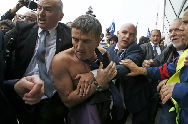 A shirtless Xavier Broseta (2nd L), Executive Vice President for Human Resources and Labour Relations at Air France, is evacuated by security after employees interrupted a meeting with staff representatives at the Air France headquarters building at the Charles de Gaulle International Airport in Roissy, near Paris, France, October 5, 2015. (Photo by Jacky Naegelen/Reuters)