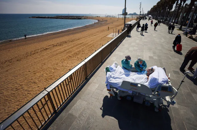 COVID-19 patient, Joan Soler Sendra, 63, who is deaf-mute, reads the lips and gestures of doctor Andrea Castellvi as he watches the sea as part of a “sea therapy”, 114 days after he was admitted to Hospital del Mar, in Barcelona, Spain on March 25, 2021. (Photo by Nacho Doce/Reuters)