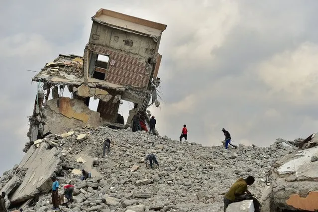 People salvage construction material on September 13, 2018, at a demolition site with precariously tilting rubble after government bulldozers knocked down a mall said to be illegall for having been built on a river bed in the Kenyan capital, Nairobi. (Photo by Tony Karumba/AFP Photo)