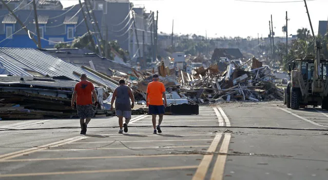 People walk amidst destruction on the main street of Mexico Beach, Fla., in the aftermath of Hurricane Michael on Thursday, October 11, 2018. (Photo by Gerald Herbert/AP Photo)