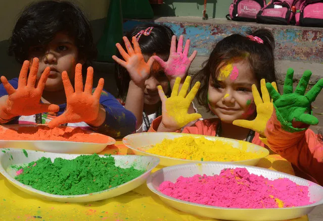 Indian children from the Bright Academy pose with colored powder known as gulal used during the Holi festival in Siliguri  on March 4, 2015.   'Holi', the festival of colours, is a riotous celebration of the coming of spring and falls on the day after full moon annually in March. Revellers spray coloured powder and water on each other with great gusto, whilst adults extend the hand of peace.   AFP PHOTO / Diptendu DUTTA        (Photo credit should read DIPTENDU DUTTA/AFP/Getty Images)