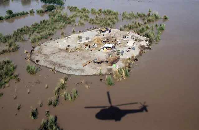 The shadow of a Pakistani army helicopter is seen next to land surrounded by flood water where affected villagers gathered to seek higher ground in the Rajanpur district, in Punjab province, on August 6, 2015. A spokesman for Pakistan's National Disaster Management Agency said that 116 people had died and more than 850,000 people had been affected around the country by this year's monsoon floods. (Photo by S.S. Mirza/AFP Photo)