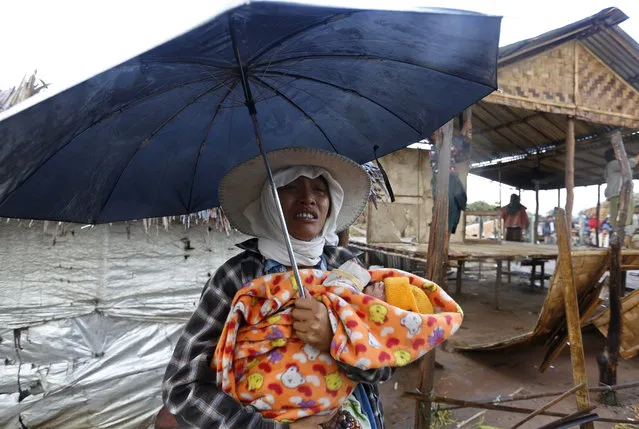 A woman holding her 14-day-old child and an umbrella cries as her house is being destroyed by authorities at a slum area in Mingalardon Township, outskirt of Yangon, Myanmar, 26 January 2016. Myanmar authorities cracked down about 400 households, including huts and houses which were illegally built on the municipal land. (Photo by Nyein Chan Naing/EPA)