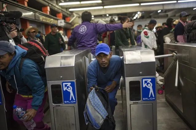A Central American migrant bypasses a subway turnstile after leaving the temporary shelter at the Jesus Martinez stadium, in Mexico City, Friday, November 9, 2018. About 500 Central American migrants headed out of Mexico City on Friday to embark on the longest and most dangerous leg of their journey to the U.S. border, while thousands more were waiting one day more at the stadium. (Photo by Rodrigo Abd/AP Photo)