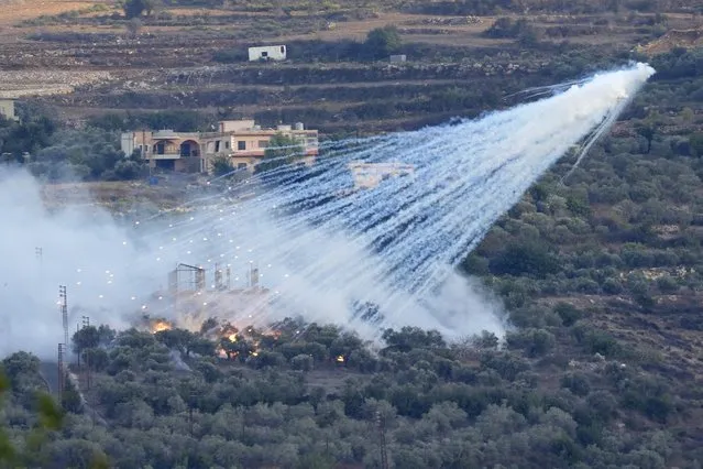 A shell from Israeli artillery explodes over a house in al-Bustan, a Lebanese border village with Israel, south Lebanon, Sunday, October 15, 2023. Hamas Palestinian militants in southern Lebanon fired 20 rockets into the northern Israeli towns of Schlomi and Nahariyya, the group said in a statement. They said it was “in response to the (Israeli) occupation's crimes against our people in Gaza”. (Photo by Hussein Malla/AP Photo)