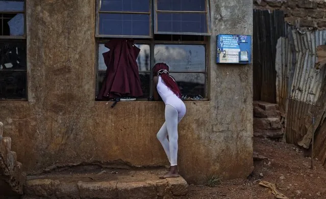 In this photo taken Friday, December 9, 2016, a young ballerina looks through the window at others practicing under the instruction of Kenyan ballet dancer Joel Kioko, 16, in a room at a school in the Kibera slum of Nairobi, Kenya. (Photo by Ben Curtis/AP Photo)