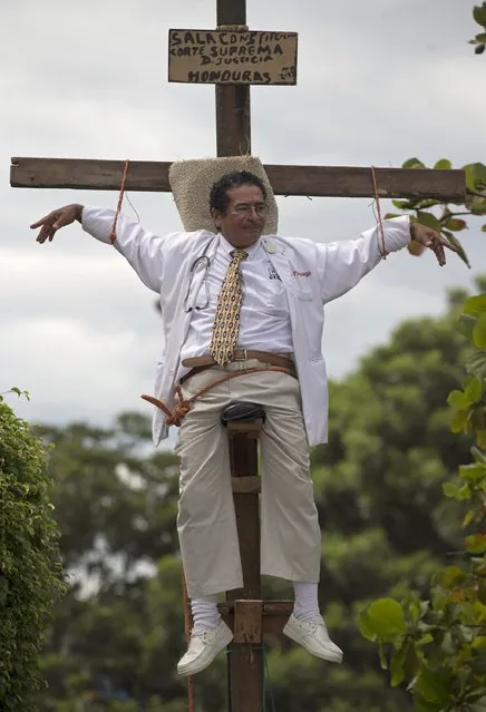 Francisco Pagoada hangs from a cross, with some support, as part of his protest against the Supreme Court that denied Pagoada's request to run as an independent candidate for mayor, in Tegucigalpa, Honduras, Wednesday, November 20, 2013. Honduras will hold general elections on Sunday. (Photo by Eduardo Verdugo/AP Photo)