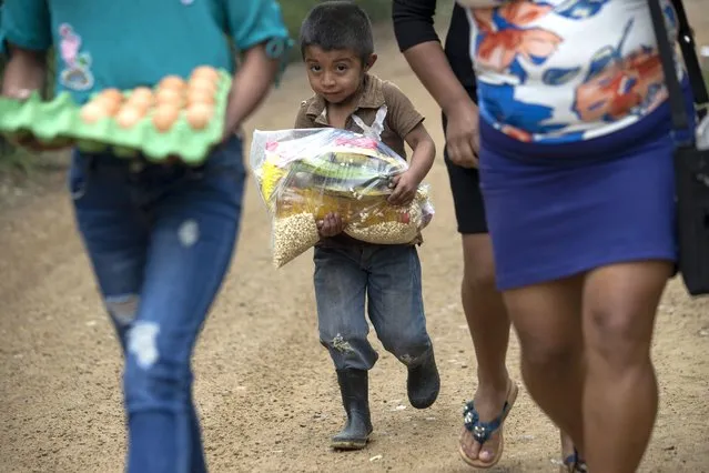 A boy helps his family carry home food that, before the COVID-19 lockdown closed schools, was fed to students as they leave the school in Tizamarte, Wednesday, December 9, 2020. Average monthly earnings here are less than the cost of the basket of basic goods. (Photo by Moises Castillo/AP Photo)