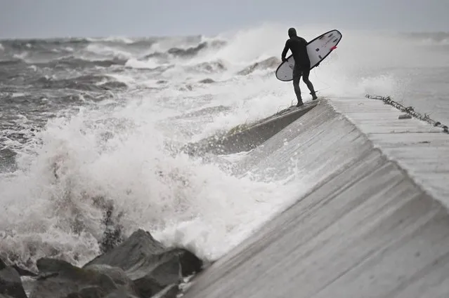 A surfer checks out the waves at Kampinge Strandbad near Hollviken, south of Malmo, Sweden as the region is hit by Storm Babet on October 20, 2023. Flights and ferries were cancelled in Scandinavia as Storm Babet moved in over the region, with meteorologists forecasting gale force winds and flooding in Denmark and southern Sweden. (Photo by Johan Nilsson/TT via AFP Photo)