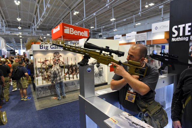 Derek Dimiceli looks at rifles and scopes in the trade booth area during the National Rifle Association's annual meeting in Nashville, Tennessee, April 11, 2015. (Photo by Harrison McClary/Reuters)