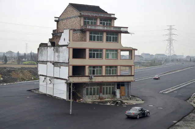A car stops beside a house in the middle of a newly built road in Wenling, Zhejiang province, China, November 22, 2012. An elderly couple refused to sign an agreement to allow their house to be demolished. They say that compensation offered is not enough to cover rebuilding costs, according to local media. Their house is the only building left standing on a road which is paved through their village. (Photo by Reuters/China Daily)