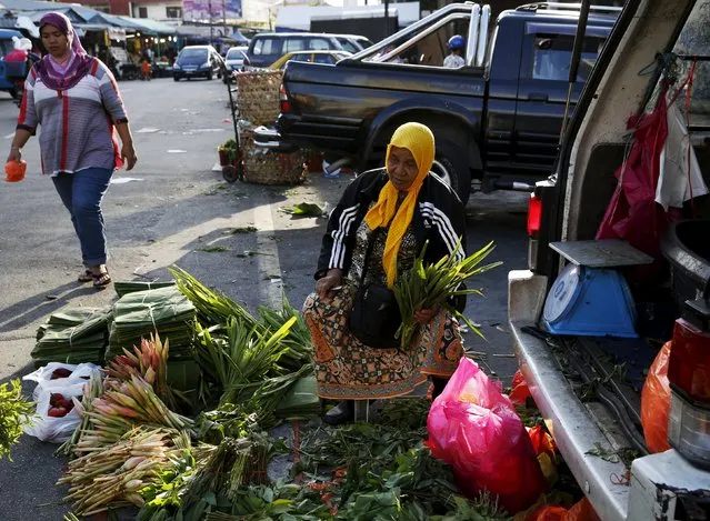 A woman sells vegetables out of the boot of her car outside a market in Kuala Lumpur, Malaysia, February 18, 2016. (Photo by Olivia Harris/Reuters)
