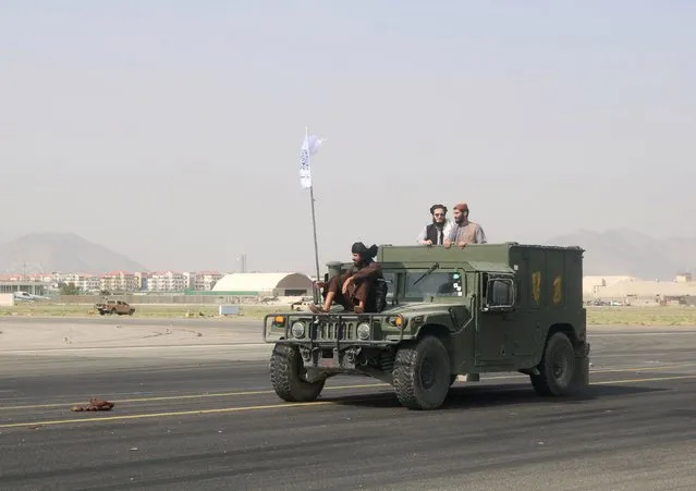 Taliban fighters ride on a Humvee as its tears across the tarmac at the airport in Kabul on August 31, 2021. (Photo by Reuters/Stringer)