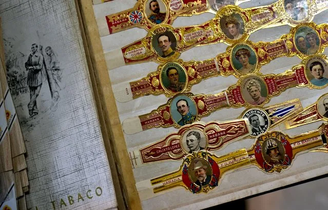 In this Monday, February 18, 2019 photo, antique cigar vitolas from before 1900, which are wrapped around cigars, are displayed in an album during the inauguration ceremony for the XXI Cigar Festival in Havana, Cuba. The annual five-day bash brings together cigar sophisticates from around the world, and culminates with a gala dinner, followed by an auction of humidors worth hundreds of thousands of dollars, with the proceeds donated to the public health system. (Photo by Ramon Espinosa/AP Photo)