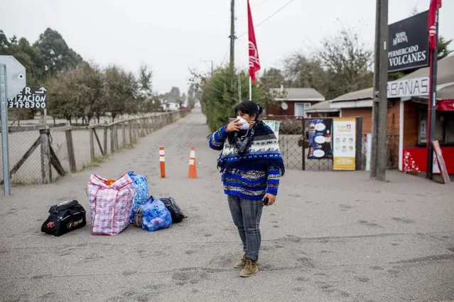 A woman holds a mask to her face as she stands with her belongings before evacuating the town of Ensenada, Chile after the Calbuco volcano erupted, Thursday, April 23, 2015. The volcano erupted Wednesday for the first time in more than 42 years, billowing a huge ash cloud over a sparsely populated, mountainous area in southern Chile. (Photo by Pablo Sanhueza Gutierrez/AP Photo)