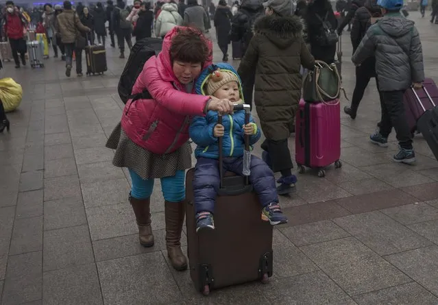 A Chinese woman pushes her child on a suitcase as they arrive for a train at Beijing Railway Station on January 26, 2017 in Beijing, China. (Photo by Kevin Frayer/Getty Images)