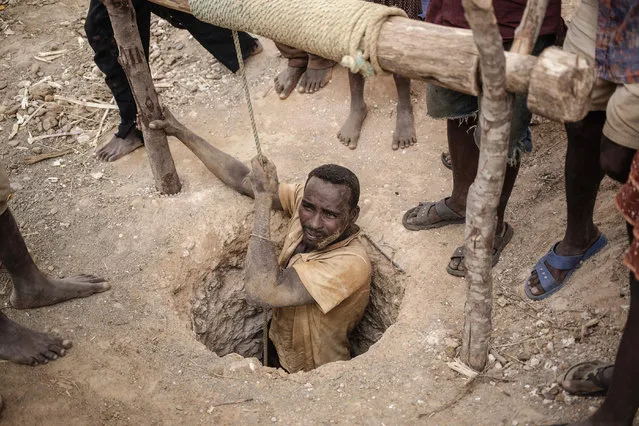 A malagasy Sapphire miner resurfaces from a hole in the ground during mining at an informal Sapphire mine on December 2, 2016 on the outskirts of Sakaraha, Madagascar. (Photo by Gianluigi Guercia/AFP Photo)