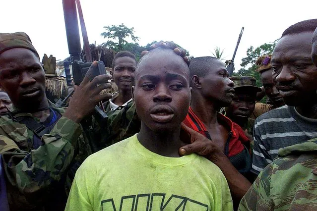 Revolutionary United Front (RUF) rebel Obai Kanu, 18, (C) is surrounded by government troops after he was captured following heavy fighting in Rogberi junction some 100 km east northeast of Freetown, Sierra Leone, May 23, 2000. (Photo by Yannis Behrakis/Reuters)