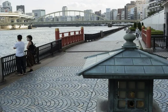 A man and a woman wearing face masks watch the Sumida River as they visit its riverside walking trail in Tokyo, Thursday, September 16, 2021. (Photo by Hiro Komae/AP Photo)