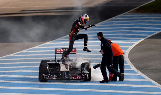 Toro Rosso driver Jean-Eric Vergne jumps from his car as fire marshals use fire extinguishers, after smoke was seen coming from the car, during the 2014 Formula One Testing at the Circuito de Jerez, Jerez, Spain, on January 30, 2014. (Photo by Martin Rickett/PA Wire)