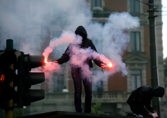 Demonstrators wearing dark hood on their head, fire flares during a demonstration in downtown Milan on April 30, 2015 to protest against the World Exposition Milano 2015 (Universal Exposition) saying that the massively indebted Italian state should not be ploughing money into an ephemeral event at a time of economic hardship for many Italians. (Photo by Filippo Monteforte/AFP Photo)