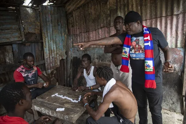 Jimmy Cherizier, aka Barbecue, a former policeman who leads the G9 gang coalition, visits with friends as they play a game of dominoes in the Cite Soleil shantytown of Port-au-Prince, Haiti, Sunday, October 3, 2021. Despite all appearances, he says he is not positioning himself for a political career. He claims not to have any political affiliation or party and says he does not see himself “as a candidate in a system that I see as corrupt”. (Photo by Rodrigo Abd/AP Photo)