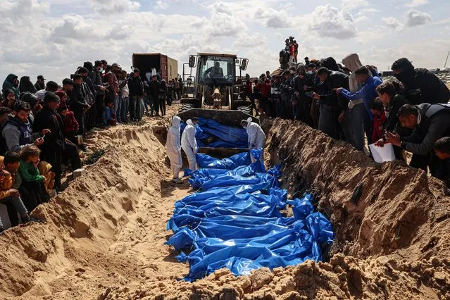 Mourners watch as medical personnel prepare the bodies of 47 Palestinians, that were taken and later released by Israel, during a mass funeral in Rafah in the southern Gaza Strip on March 7, 2024, amid ongoing battles between Israel and the militant group Hamas. Gaza's Hamas-run government media office said Thursday that Israel had returned dozens of bodies that had been exhumed from graves in the besieged territory in recent weeks. (Photo by Said Khatib/AFP Photo)