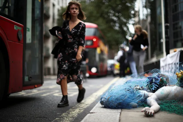A person walks by an Ocean Rebellion activist taking part in a demonstration outside Department for Environment, Food and Rural Affairs (DEFRA) in London, Britain on September 15, 2021. (Photo by Hannah McKay/Reuters)