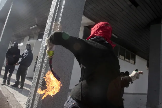 A masked demonstrator readies to throw a petrol bomb towards the police during a protest at the University of Santiago, in Santiago, Chile, Thursday, May 14, 2015. (Photo by Luis Hidalgo/AP Photo)