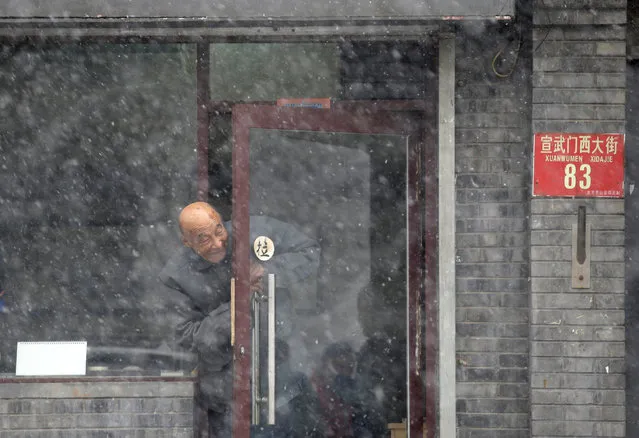 An elderly man looks out from a door during a snowfall in Beijing, China February 21, 2017. (Photo by Jason Lee/Reuters)