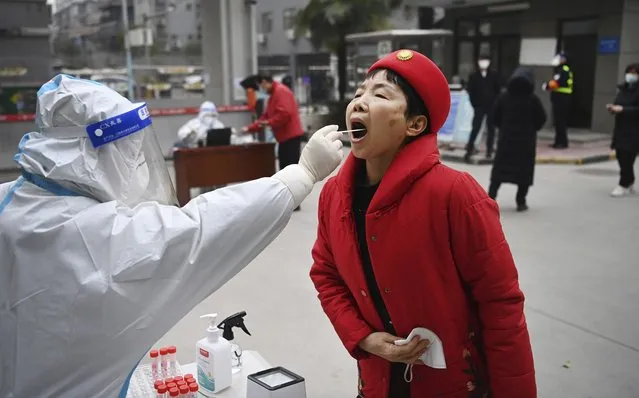 In this photo released by China's Xinhua News Agency, a worker wearing protective gear gives a COVID-19 test to a woman at a testing site in Xi'an in northwestern China's Shaanxi Province, Tuesday, January 4, 2022. China is reporting a major drop in local COVID-19 infections in the northern city of Xi'an, which has been under a tight lockdown for the past two weeks. (Photo by Tao Ming/Xinhua via AP Photo)