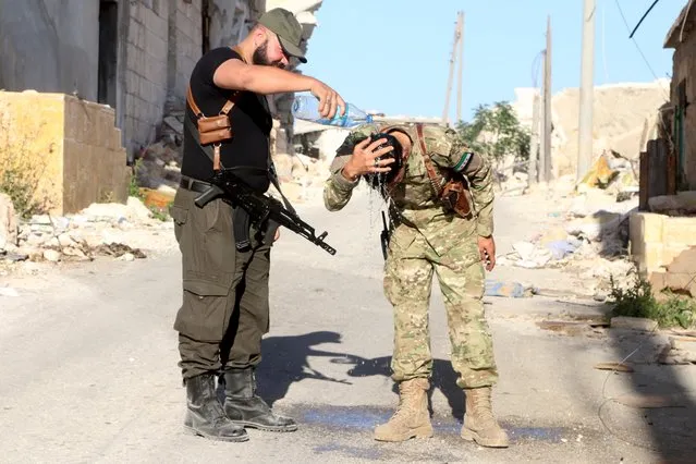 A Harakat Nour al-Din al-Zenki fighter pours water over the head of a fellow fighter to cool down in Handarat area, north of Aleppo, Syria, April 19, 2016. (Photo by Abdalrhman Ismail/Reuters)