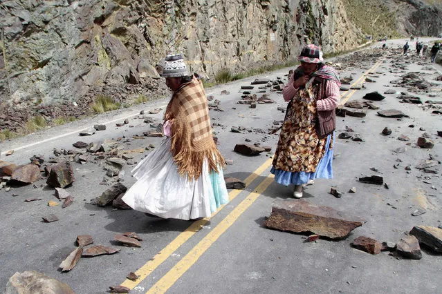 Women walk on a road blocked by independent miners in the La Cumbre mountain pass near La Paz, Bolivia, on April 1, 2014. Thousands of independent miners are blocking the main routes along Bolivia to reject a new mining law by President Evo Morales’ government, which they say prevents them from associating with private mining firms of their choice. (Photo by David Mercado/Reuters)