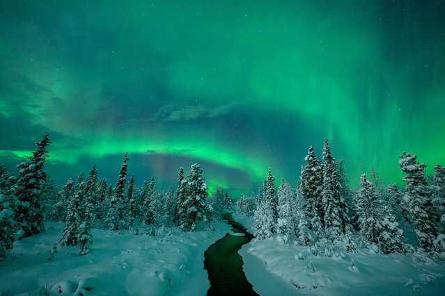 The Northern Lights or Aurora Borealis shine over a stream near the Icehotel on December 16, 2023 in Jukkasjarvi, Sweden. Since 1989, the Icehotel – part hotel, part art exhibition – has been crafted annually from ice taken from the Torne River. (Photo by Roy Rochlin/Getty Images)