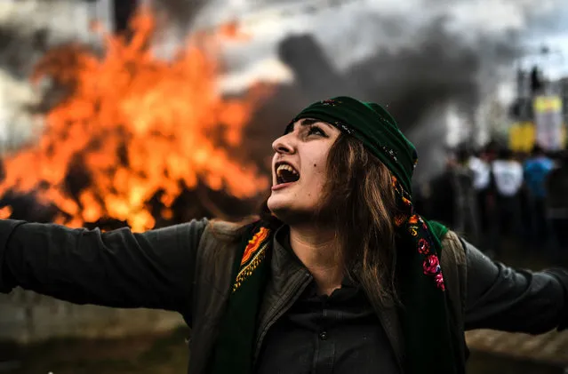A Kurdish woman dances in front of a fire as Turkish Kurds gather for Newroz celebrations for the new year in Diyarbakir, southeastern Turkey, on March 21, 2017. Newroz (also known as Nawroz or Nowruz) is an ancient Persian festival, which is also celebrated by Kurdish people, marking the first day of spring, which falls on March 21. (Photo by Bulent Kilic/AFP Photo)