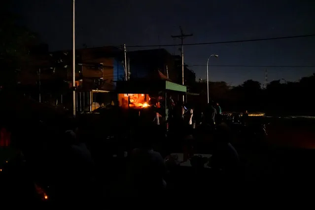 People have dinner on the dark at a street food stall, during a power cut in Tinaquillo in the state of Cojedes, Venezuela, March 20, 2016. (Photo by Carlos Garcia Rawlins/Reuters)