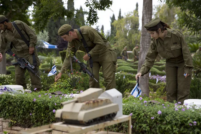 Israeli soldiers place small flags with black ribbons on the grave of fallen soldiers on the eve of memorial Day in Kiryat Shaul military cemetery in Tel Aviv, Israel, Tuesday, May 10, 2016. (Photo by Ariel Schalit/AP Photo)