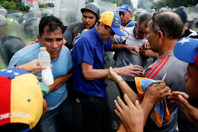 Venezuelan opposition leader and Governor of Miranda state Henrique Capriles (C) recovers from tear gas after clashes with riot policemen during a rally to demand a referendum to remove President Nicolas Maduro in Caracas, Venezuela, May 11, 2016. (Photo by Carlos Garcia Rawlins/Reuters)