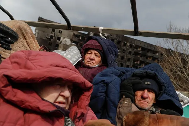 Evacuees fleeing Ukraine-Russia conflict sit in the body of a cargo vehicle while waiting in a line to leave the besieged southern port city of Mariupol, Ukraine on March 17, 2022. (Photo by Alexander Ermochenko/Reuters)