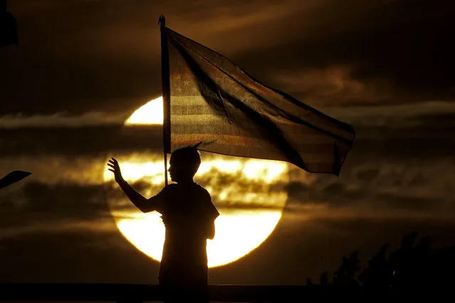 A boy waves to passing motorists to commemorate the anniversary of the Sept. 11 terrorist attacks from an overpass on Interstate 35 Wednesday, September 11, 2019, near Melvern, Kan. Area residents began manning the bridge with flags and waving to motorists on the anniversary in 2002 and have done it ever since. (Photo by Charlie Riedel/AP Photo)