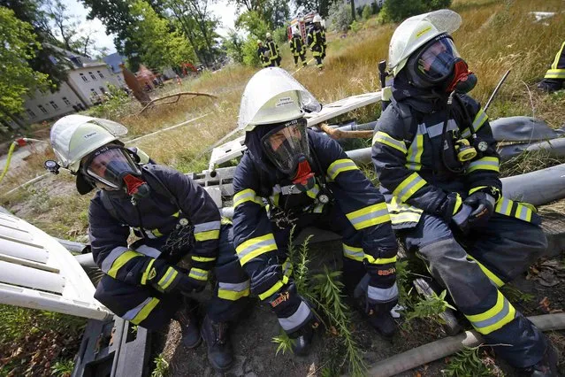 Three firefighters rest after extinguishing a fire that broke out at a former U.S. airfield in Erlensee, Germany July 30, 2015. (Photo by Kai Pfaffenbach/Reuters)