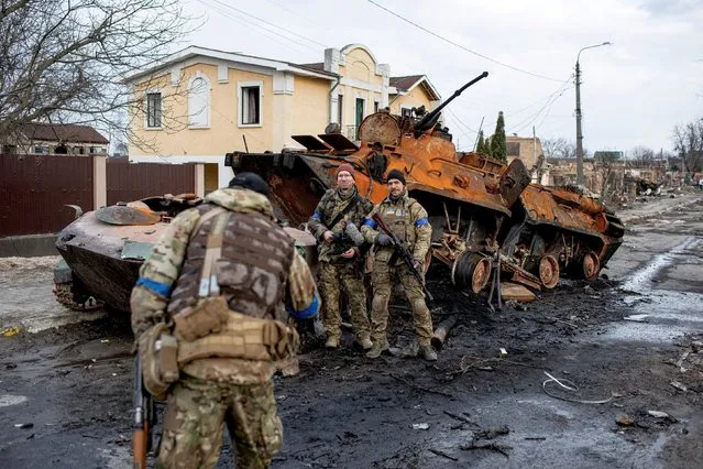 Members of territorial defense take photos next to destroyed Russian armored personnel carriers on April 4, 2022 in Bucha, Ukraine. The Ukrainian government has accused Russian forces of committing a “deliberate massacre” as they occupied and eventually retreated from Bucha, 25km northwest of Kyiv. Dozens of bodies have been found in the days since Ukrainian forces regained control of the town. (Photo by Alexey Furman/Getty Images)